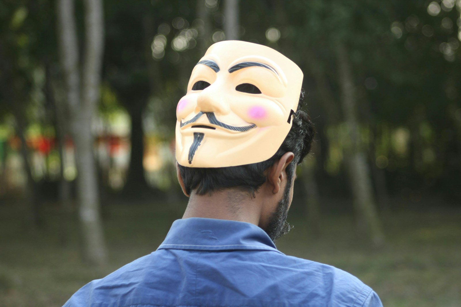 Photo by Salib Saddaf Man wearing an anonymous mask looking away.