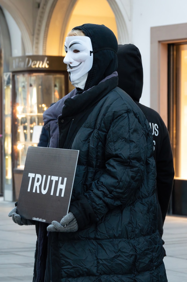 Photo by Carrie Borden a man in a mask holding a sign that says truth